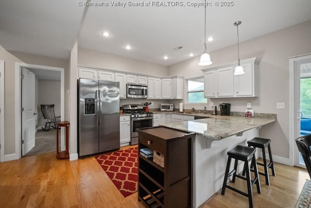 kitchen featuring stainless steel appliances, a peninsula, white cabinetry, healthy amount of natural light, and recessed lighting