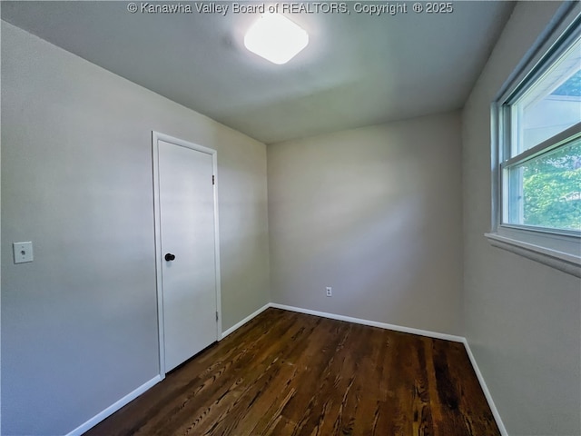 unfurnished room featuring dark wood-style flooring and baseboards