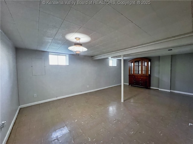 basement featuring baseboards, healthy amount of natural light, and electric panel
