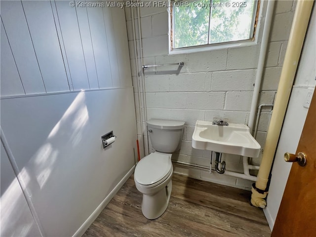 half bath with wood finished floors, toilet, and a sink