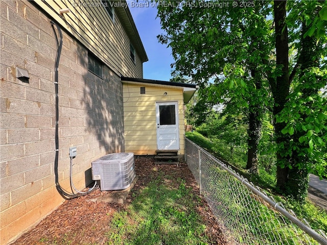 view of property exterior featuring central AC unit and fence