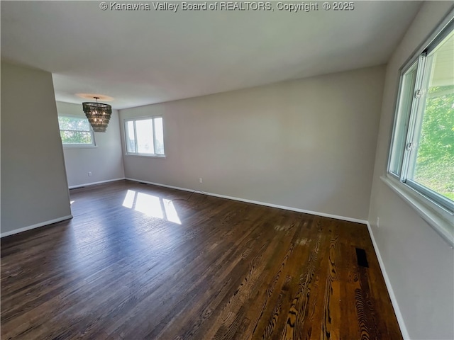 unfurnished room with dark wood-style flooring, baseboards, and a chandelier