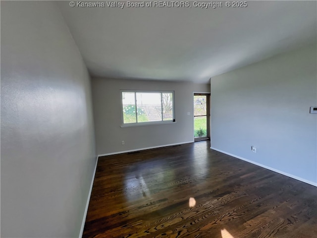 unfurnished room featuring dark wood-style flooring and baseboards