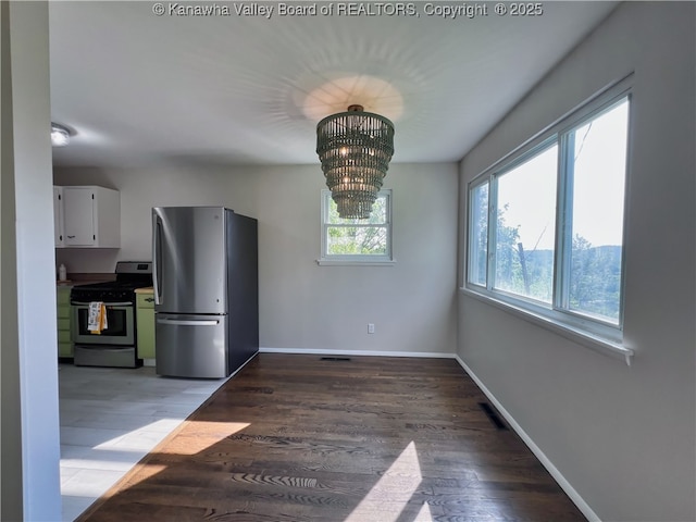 unfurnished dining area featuring wood finished floors, a chandelier, and baseboards