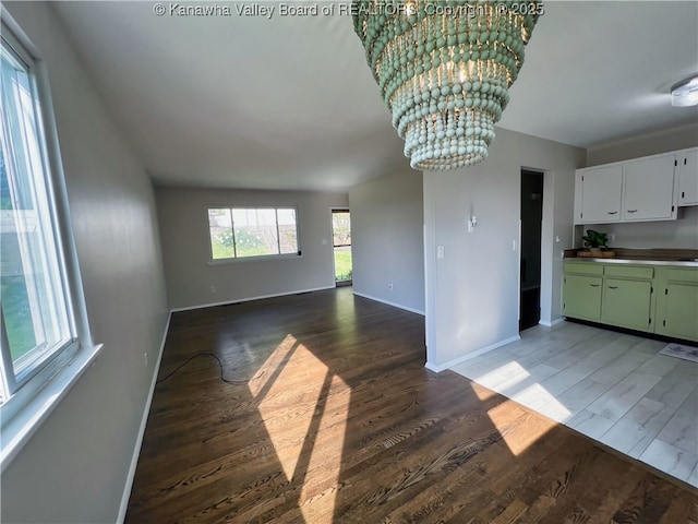 unfurnished living room featuring light wood finished floors, baseboards, and a chandelier