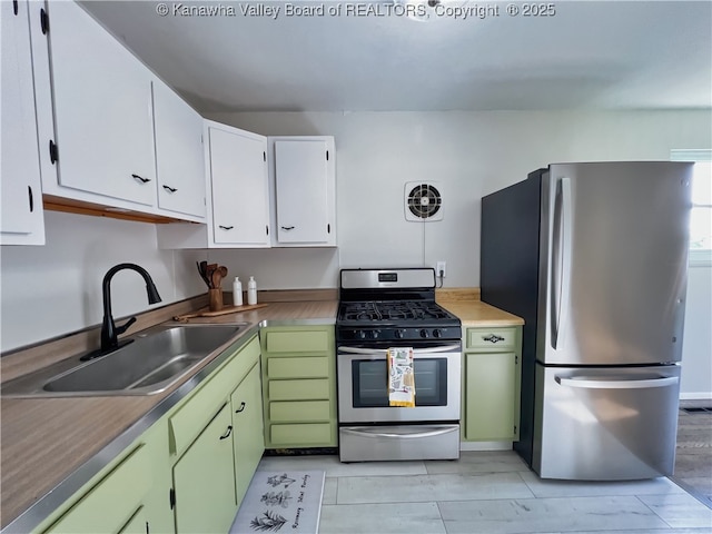 kitchen with appliances with stainless steel finishes, a sink, white cabinets, and green cabinetry