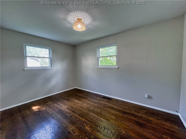 empty room featuring baseboards and dark wood-type flooring