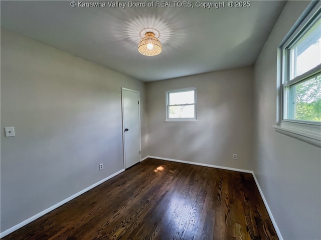 spare room featuring baseboards and wood finished floors
