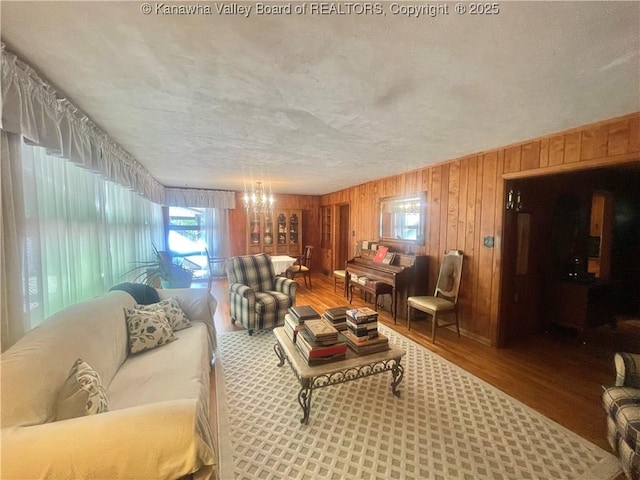 731 85th St, Marmet, WV 25315 - living area featuring healthy amount of natural light, wood finished floors, wood walls, a chandelier, and a textured ceiling