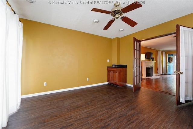 1518 Dogwood Rd, Charleston, WV 25314 - empty room with a ceiling fan, dark wood-type flooring, baseboards, and a fireplace