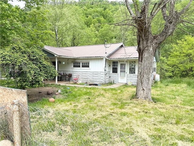 12027 Chap Rd, Wv, WV 25204 - rear view of house with stone siding, metal roof, a patio area, and a forest view