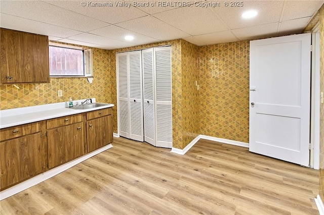 4010 Virginia Ave SE, Charleston, WV 25304 - kitchen featuring a sink, a paneled ceiling, brown cabinetry, light countertops, and light wood-type flooring