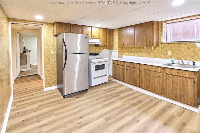 4010 Virginia Ave SE, Charleston, WV 25304 - kitchen with freestanding refrigerator, white range with electric stovetop, under cabinet range hood, a sink, and light wood-style floors
