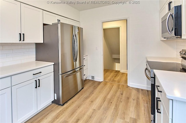 4010 Virginia Ave SE, Charleston, WV 25304 - kitchen with stainless steel appliances, tasteful backsplash, light countertops, white cabinets, and light wood finished floors