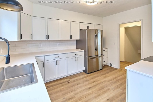 4010 Virginia Ave SE, Charleston, WV 25304 - kitchen featuring freestanding refrigerator, a sink, light wood finished floors, and white cabinetry