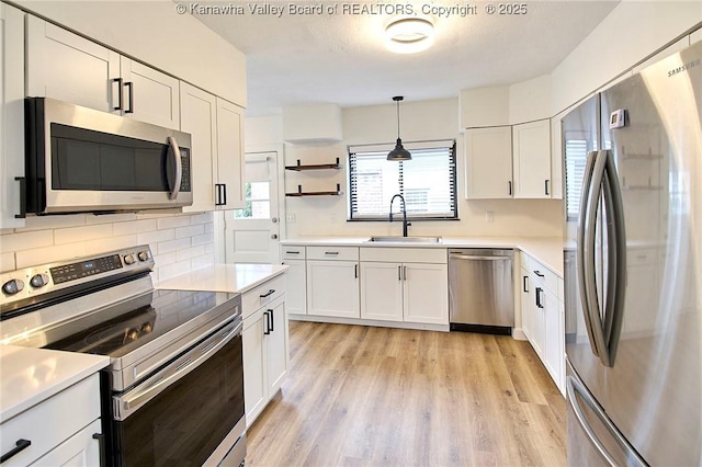 4010 Virginia Ave SE, Charleston, WV 25304 - kitchen with appliances with stainless steel finishes, a sink, white cabinetry, and light wood-style floors