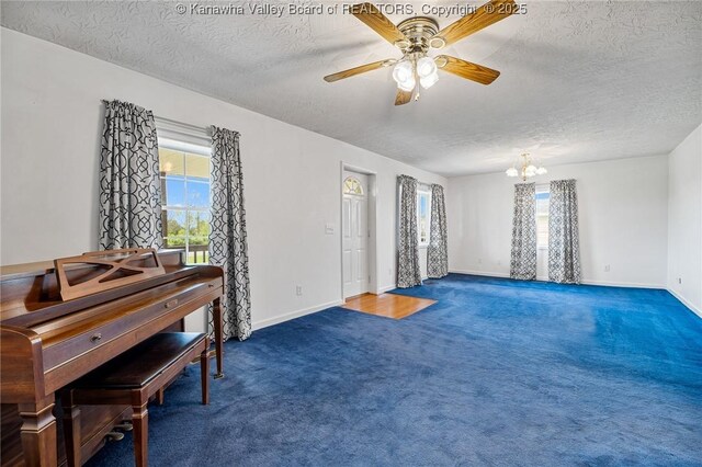 living area with plenty of natural light, a textured ceiling, carpet floors, a chandelier, and ceiling fan