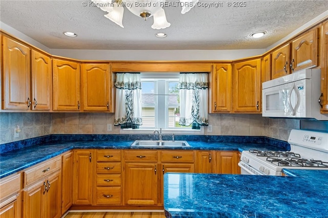 kitchen featuring white appliances, a sink, brown cabinets, tasteful backsplash, and a textured ceiling