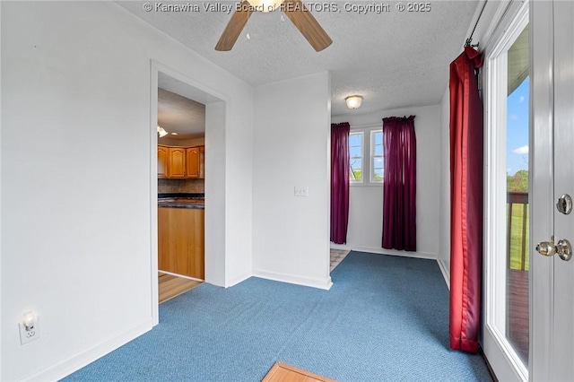 carpeted empty room featuring ceiling fan, a textured ceiling, and baseboards