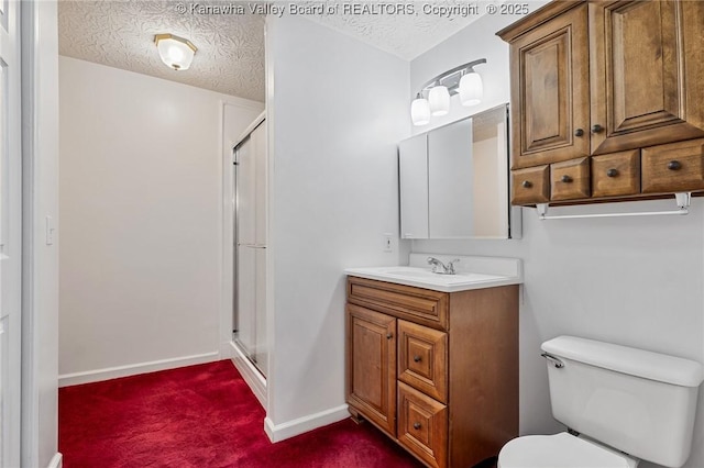 full bath featuring a stall shower, a textured ceiling, toilet, baseboards, and vanity