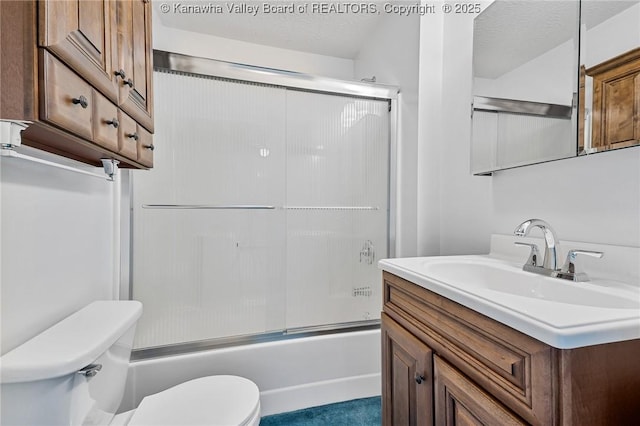 bathroom with toilet, combined bath / shower with glass door, and vanity