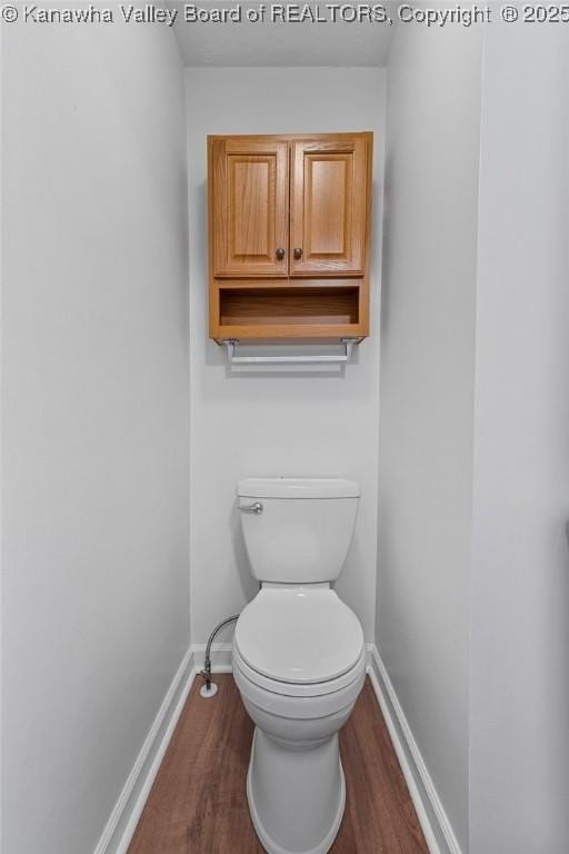 bathroom featuring baseboards, wood finished floors, and toilet