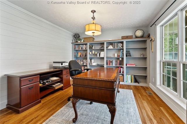home office with light wood-type flooring and wooden walls