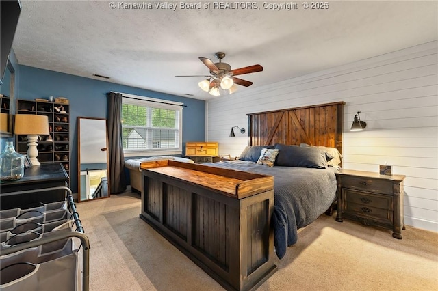 bedroom with light colored carpet, wooden walls, and a ceiling fan