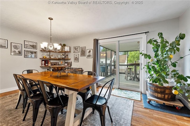 dining space with wood finished floors, a chandelier, and baseboards