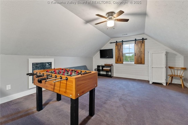 game room featuring a textured ceiling, ceiling fan, baseboards, vaulted ceiling, and dark colored carpet