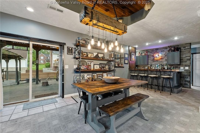 dining area featuring bar with sink, light tile patterned flooring, recessed lighting, and a textured ceiling