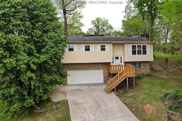 bi-level home featuring a chimney, brick siding, concrete driveway, and an attached garage