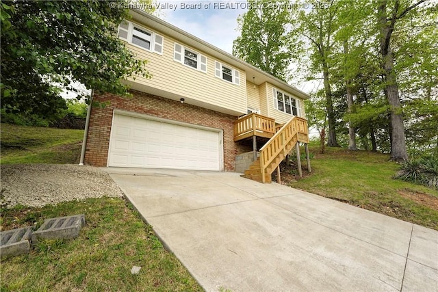 view of front of house featuring an attached garage, concrete driveway, brick siding, a front lawn, and a wooden deck