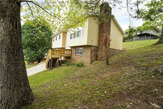 back of property with brick siding, a chimney, a lawn, and a wooden deck