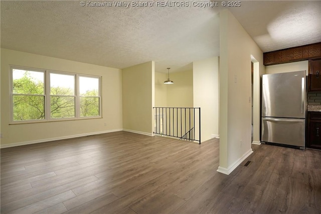 unfurnished room with dark wood-style floors, a textured ceiling, and baseboards