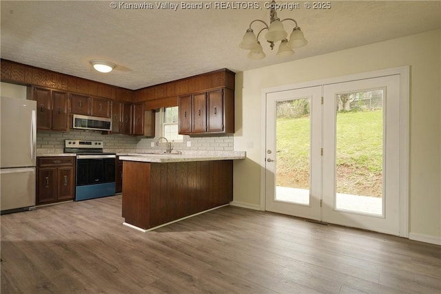 kitchen with stainless steel appliances, a chandelier, light countertops, backsplash, and a textured ceiling