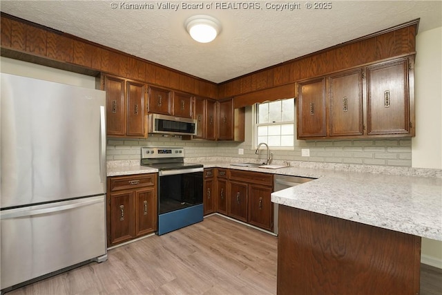 kitchen featuring stainless steel appliances, a textured ceiling, light countertops, a sink, and decorative backsplash