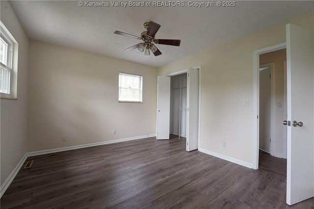 unfurnished bedroom featuring dark wood finished floors, a closet, and baseboards