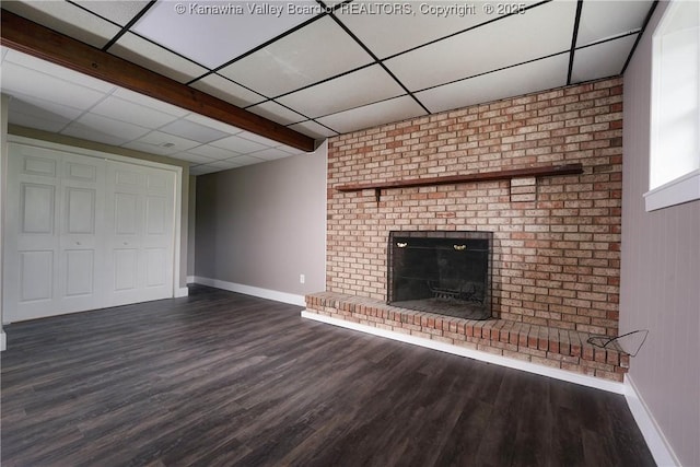 unfurnished living room featuring baseboards, a brick fireplace, wood finished floors, and a paneled ceiling