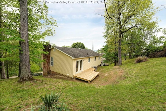 back of property featuring a deck, a lawn, a chimney, and central AC unit