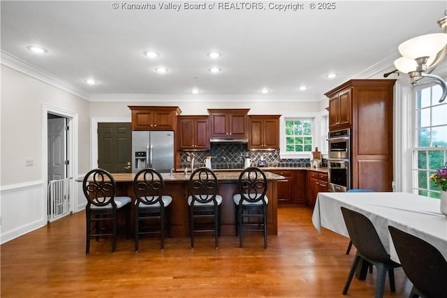 12 W Coventry Rd, South Charleston, WV 25309 - kitchen with stainless steel appliances, wood finished floors, a kitchen island with sink, crown molding, and a kitchen breakfast bar