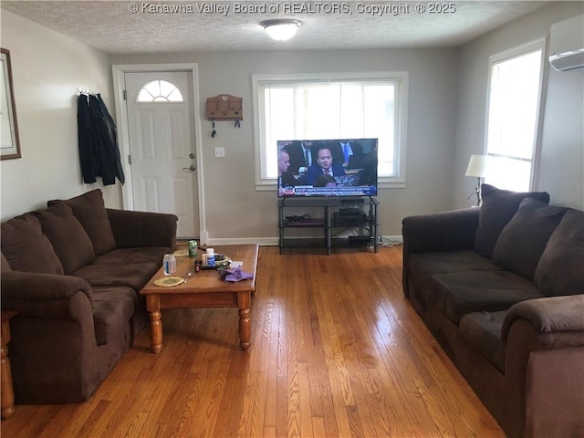 329 3rd Ave, Ripley, WV 25271 - living room with a wall mounted AC, hardwood / wood-style floors, a textured ceiling, and baseboards