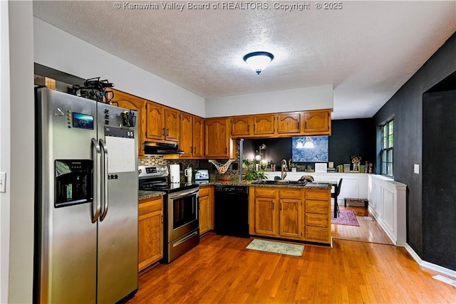 5427 Hillbrook Dr, Charleston, WV 25313 - kitchen featuring stainless steel appliances, under cabinet range hood, a sink, brown cabinetry, and a textured ceiling