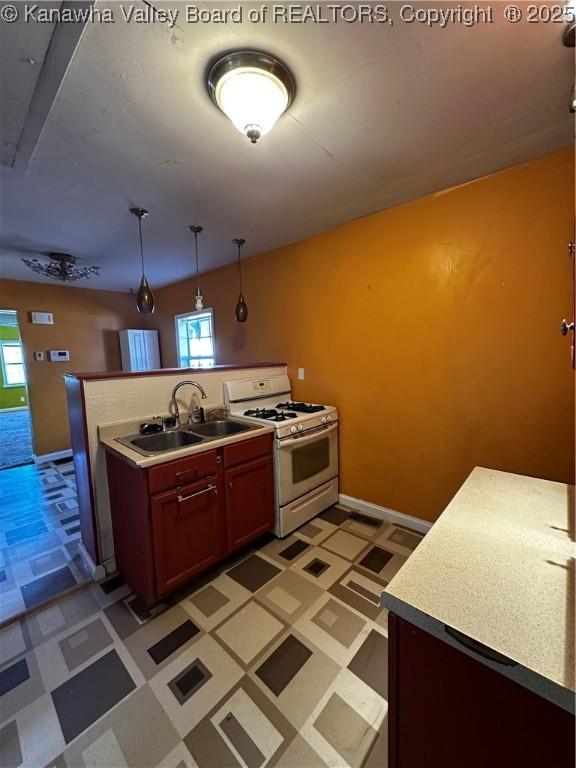 1603 Frame St, Charleston, WV 25387 - kitchen featuring white range with gas cooktop, a sink, light flooring, decorative light fixtures, and baseboards