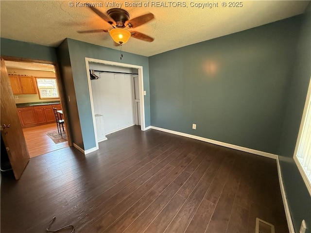 1886 Whitman Creek Rd, Whitman, WV 25652 - unfurnished bedroom with dark wood finished floors, a textured ceiling, baseboards, a closet, and a ceiling fan
