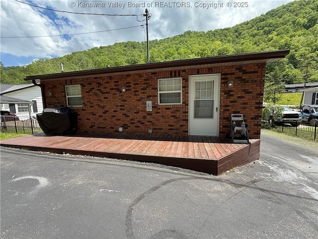 1886 Whitman Creek Rd, Whitman, WV 25652 - rear view of property featuring fence, brick siding, a view of trees, and a deck