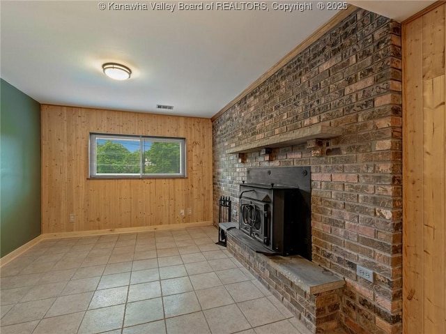 unfurnished living room featuring baseboards, wooden walls, light tile patterned floors, and a wood stove