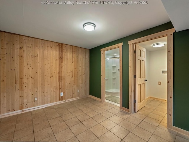 empty room featuring wood walls, light tile patterned floors, and baseboards