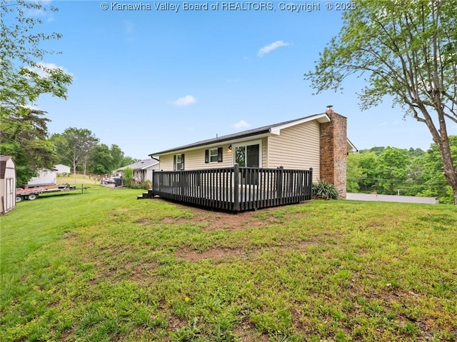 back of property with a chimney, a yard, and a wooden deck