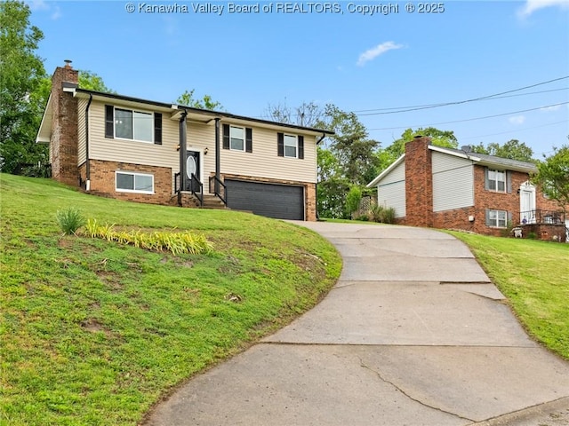 raised ranch featuring a chimney, driveway, an attached garage, and a front yard
